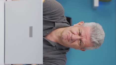 Vertical-video-of-Home-office-worker-man-looking-at-camera-depressed.